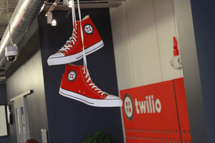 Red high-top sneakers with Twilio logo hanging in an office.