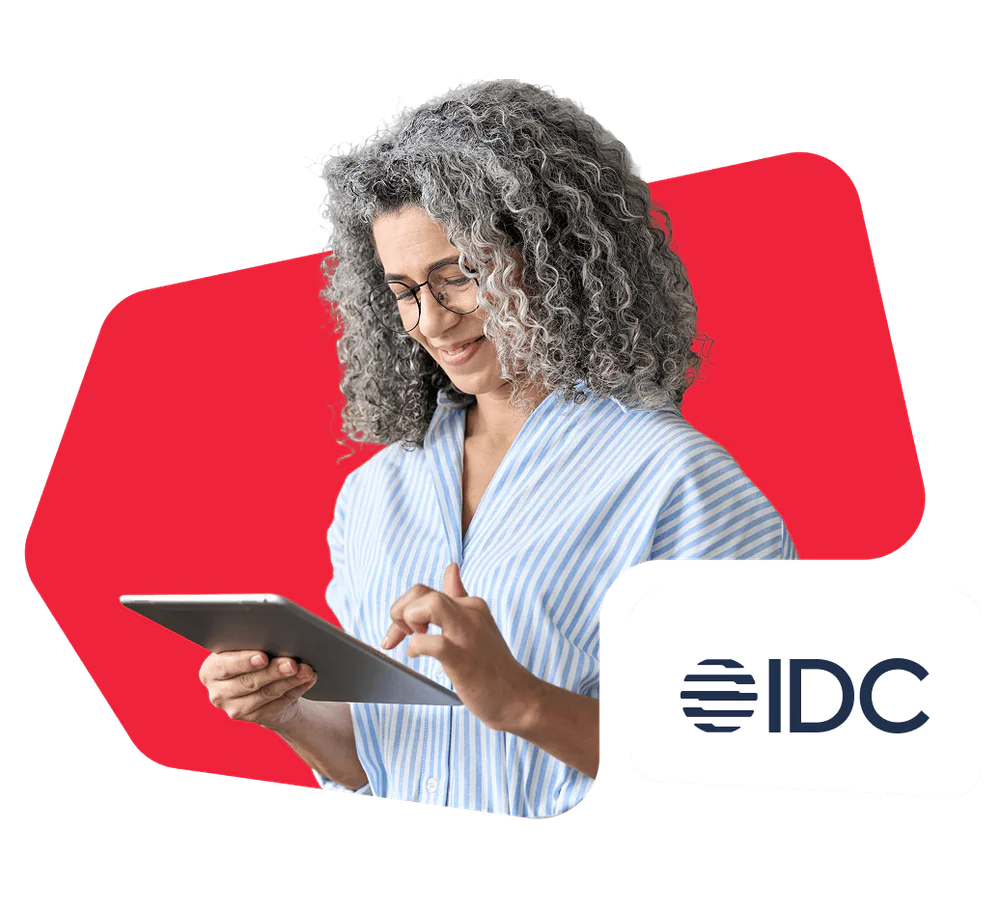 Woman with curly gray hair using a tablet, IDC logo in the corner.