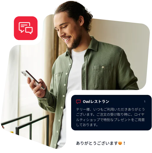 Man in green shirt reading a message on his phone with a smile on his face.