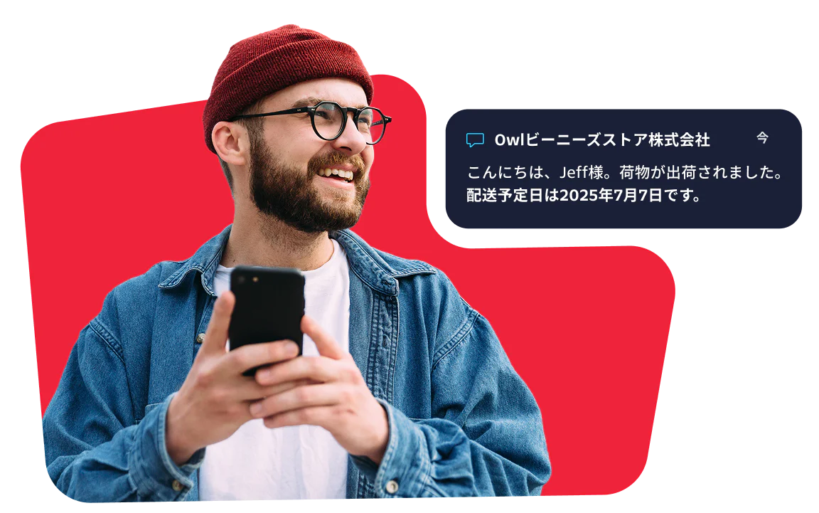 Smiling man with a red beanie checks his phone for a message about his package delivery.