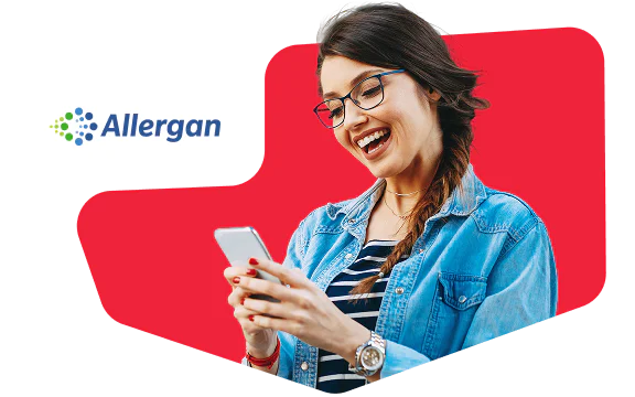 Woman in glasses and denim jacket smiling while looking at her smartphone, with Allergan logo in the background.