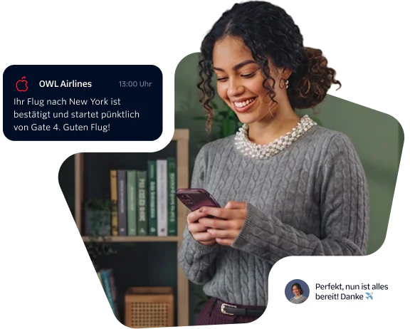 Woman smiling and looking at her phone while holding a flight confirmation message.