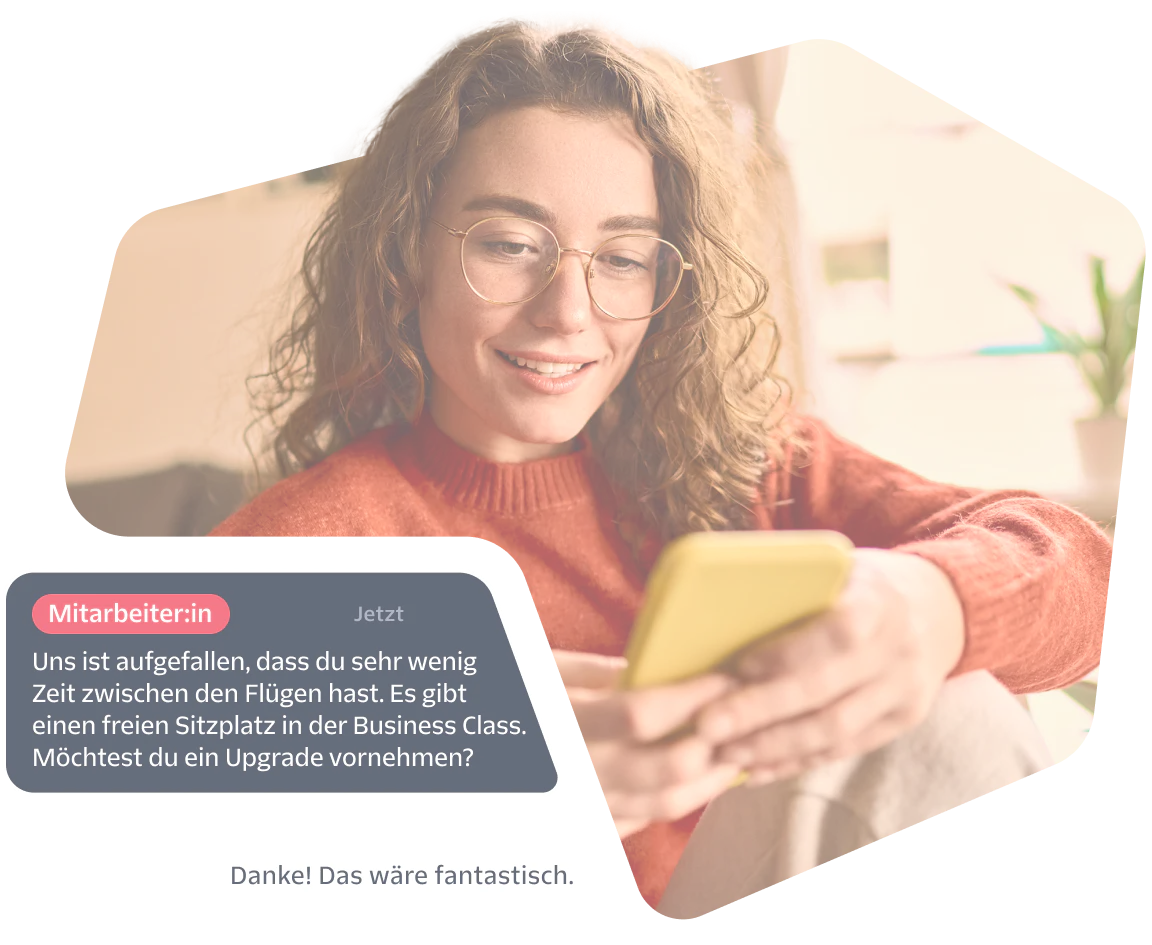 Woman smiles while reading a phone, screen shows a chat offering a business class seat upgrade.