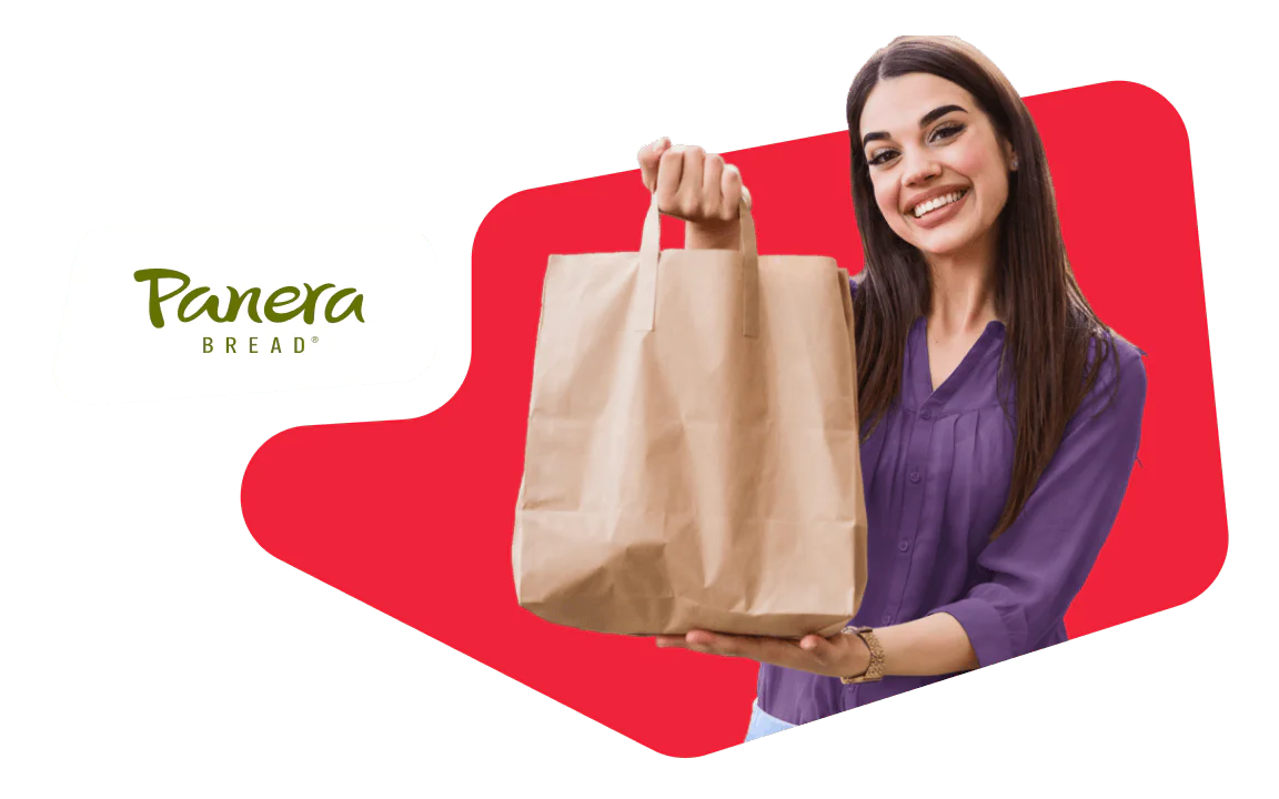 Woman smiling and holding a brown paper bag with Panera Bread logo in the background.