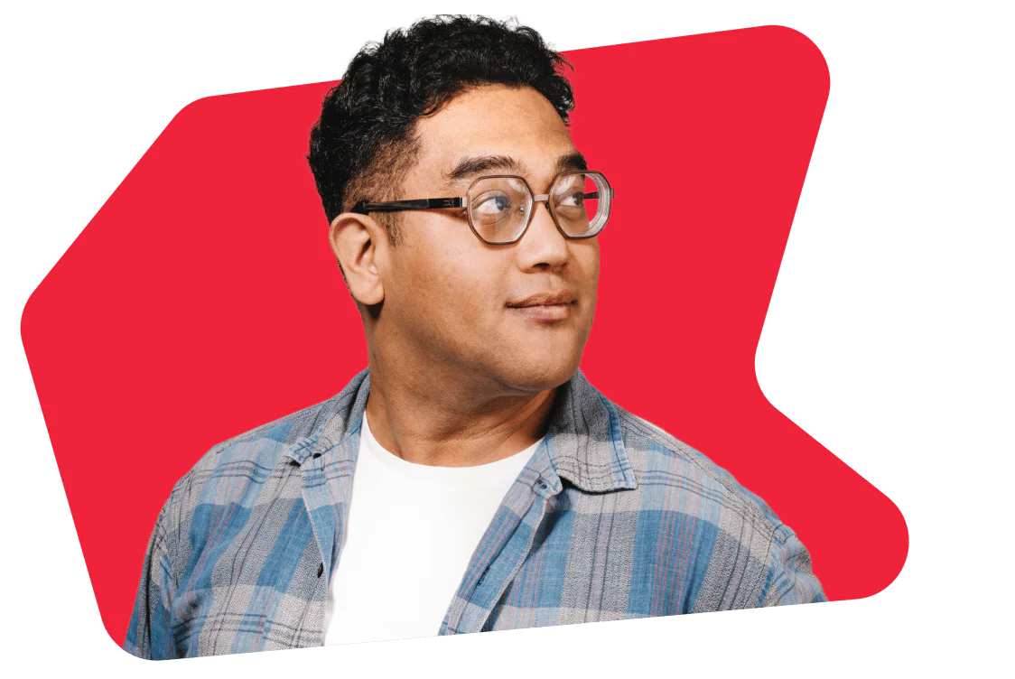 Man with glasses and a plaid shirt looks to the side with a red background.