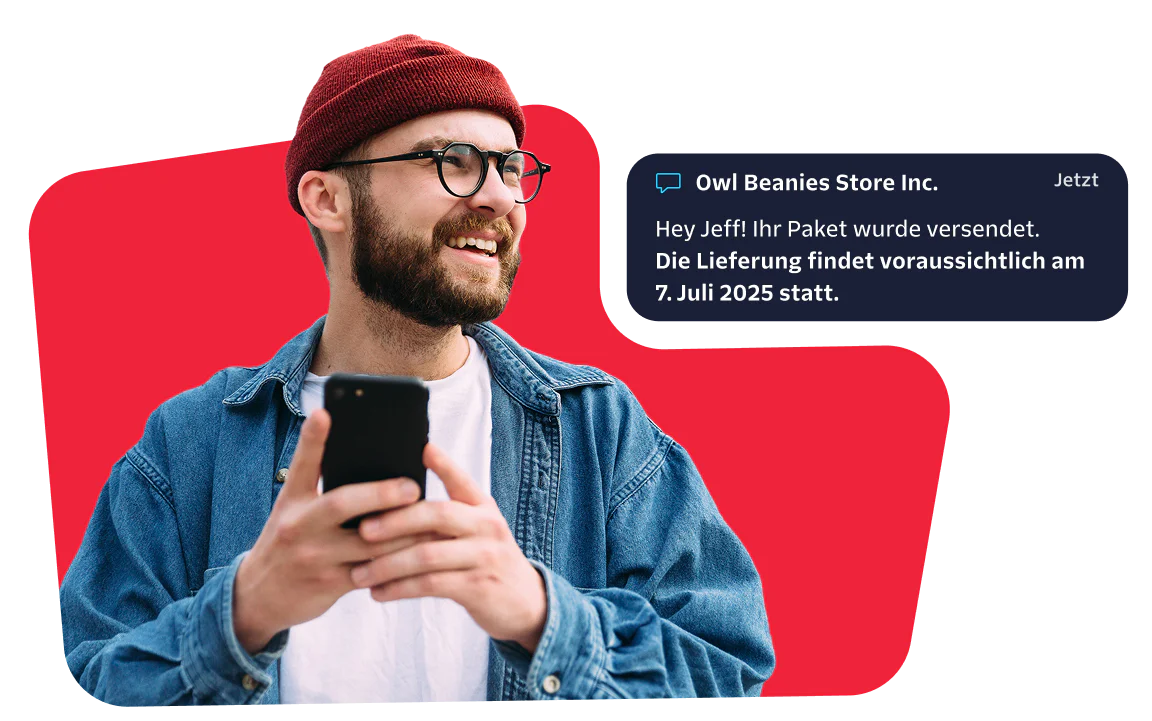 Smiling man with a red beanie checks his phone for a message about his package delivery.