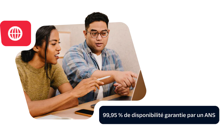 Two colleagues discussing work at a laptop showcasing a commitment to 99.95% uptime SLA