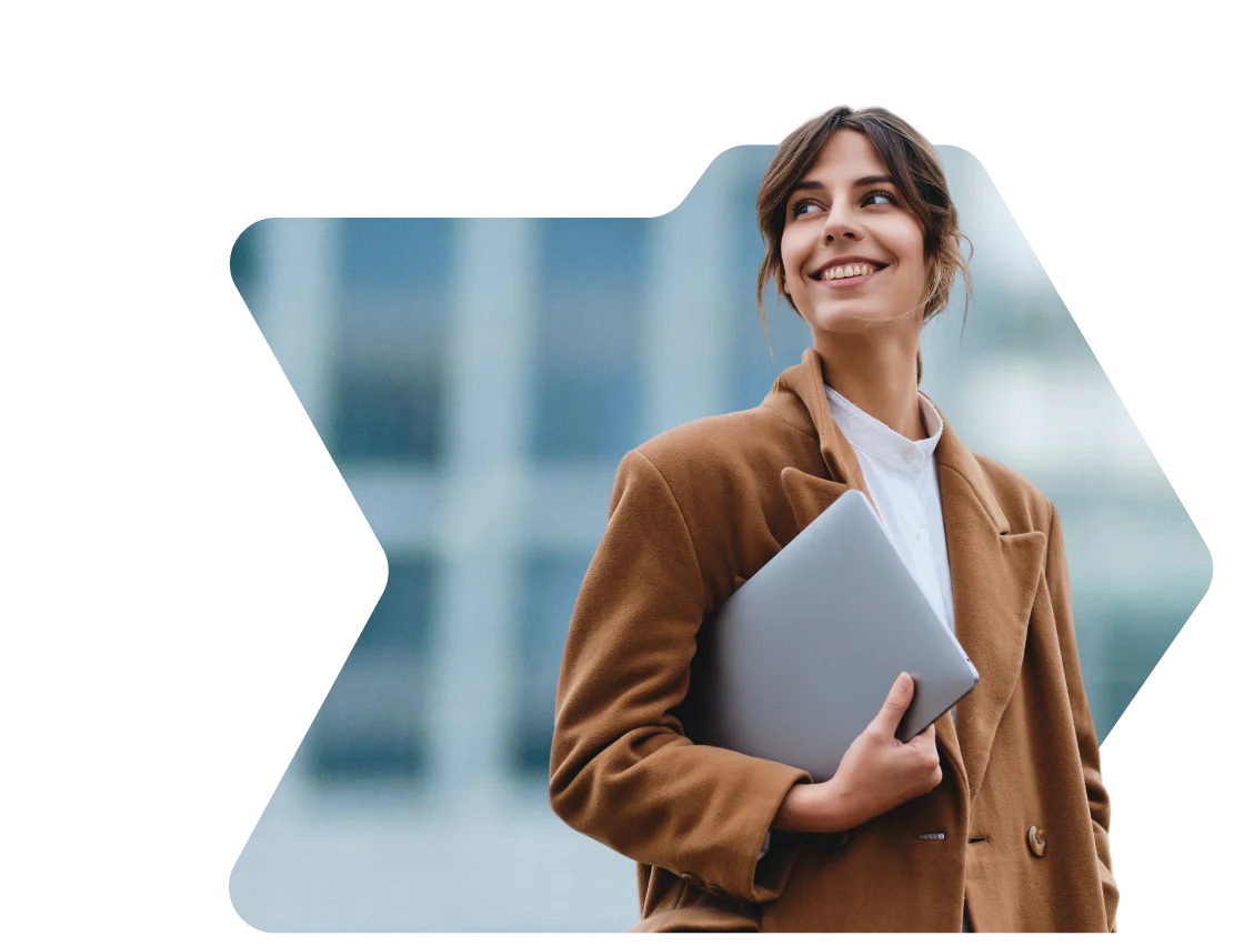Woman in brown coat smiling and holding a laptop with a birthday discount notification from OWLCLOTHES