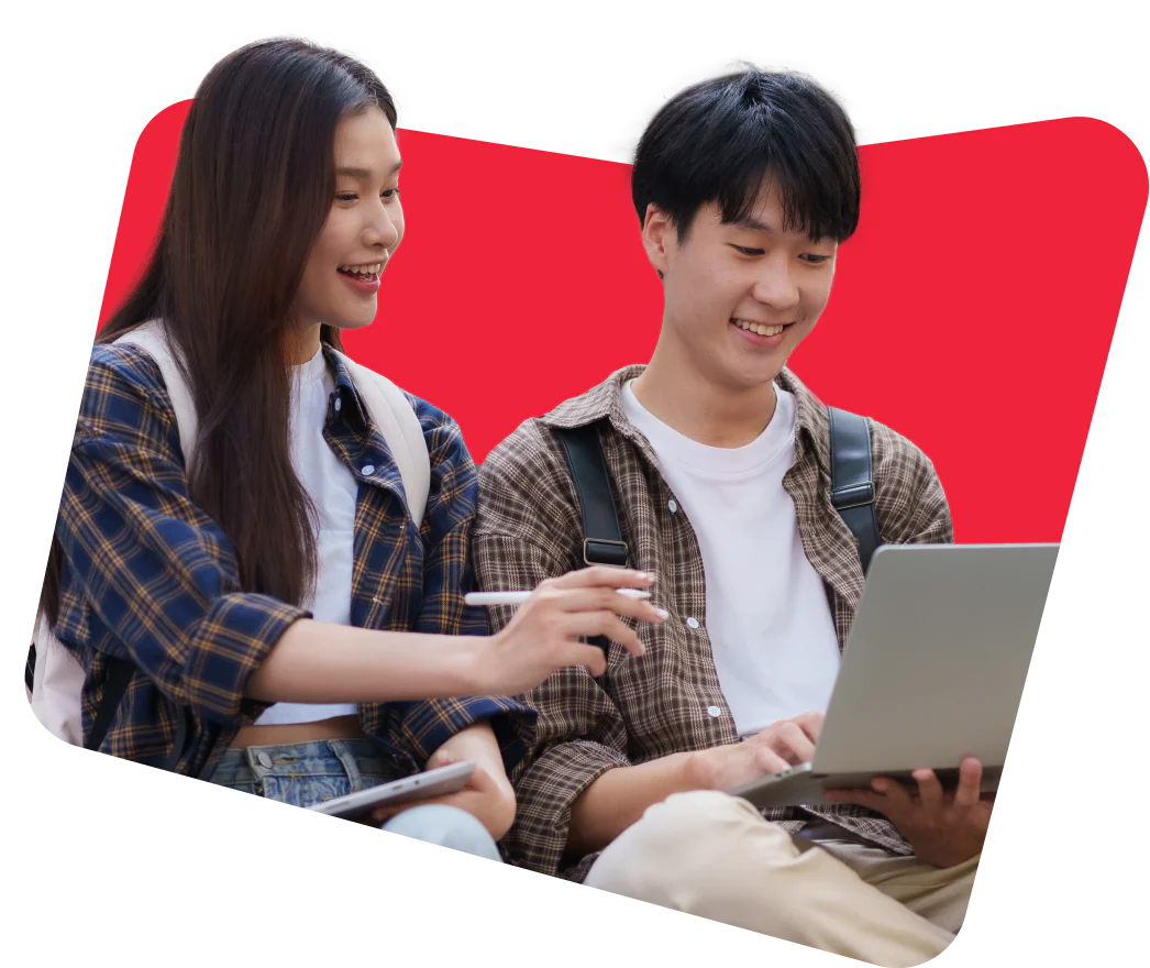 Two students with backpacks, one using a laptop while the other points at the screen.