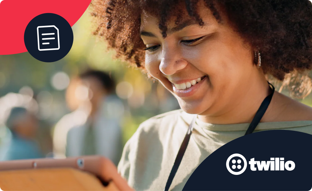 Woman with curly hair smiling while looking at her tablet at an outdoor event.