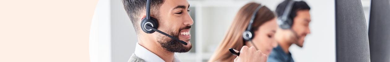 Three people wearing headsets and assisting customers in a call center.