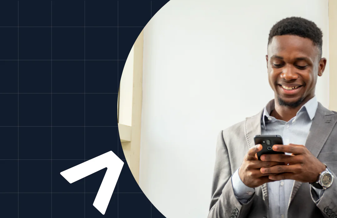 Man in gray suit smiling while using a smartphone