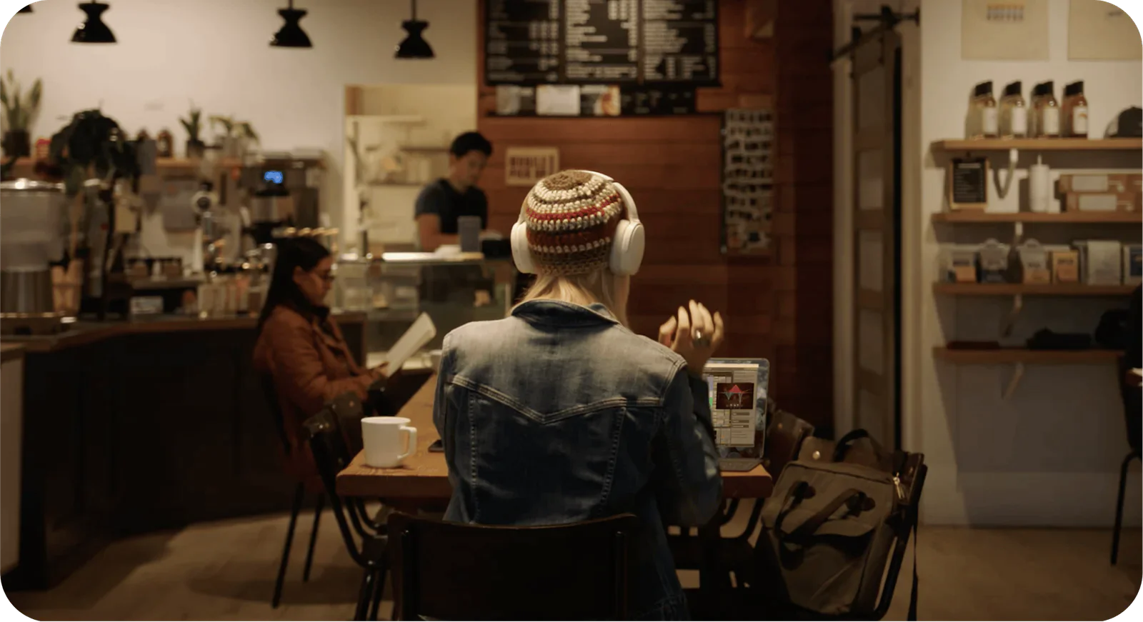 People sitting in a cozy coffee shop, reading books, and wearing headphones.