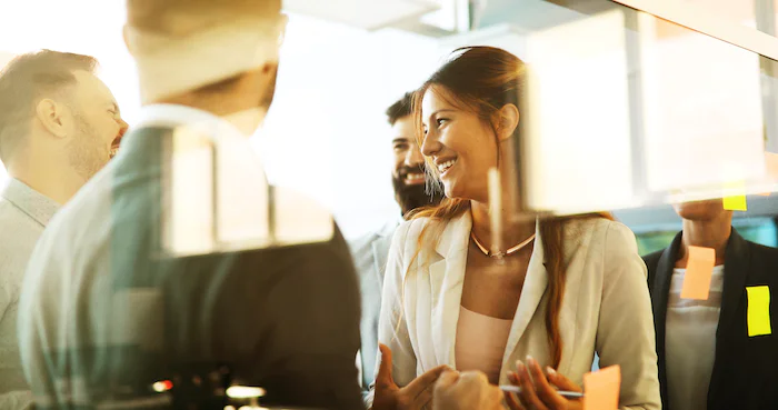 Group of business professionals having a discussion with sticky notes on the glass wall in the background.