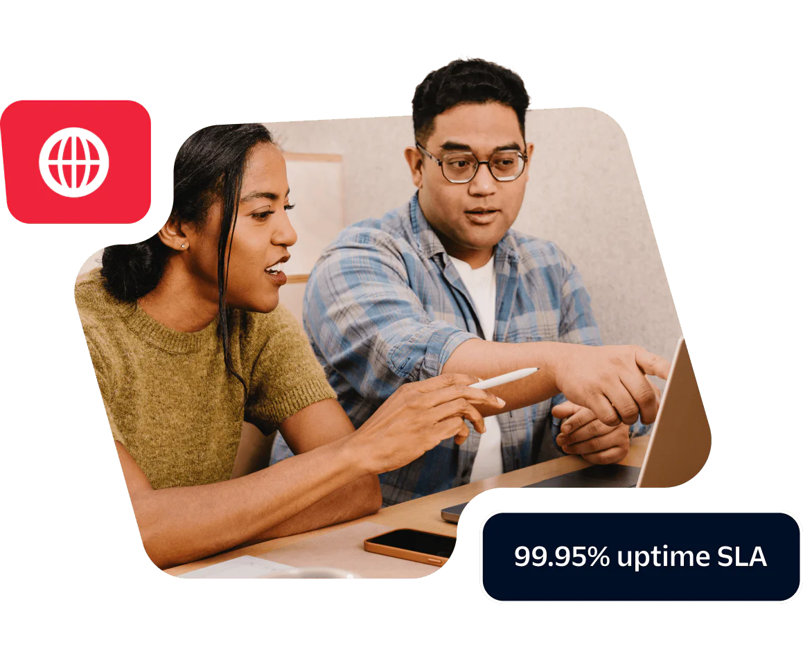 Two colleagues discussing work at a laptop showcasing a commitment to 99.95% uptime SLA