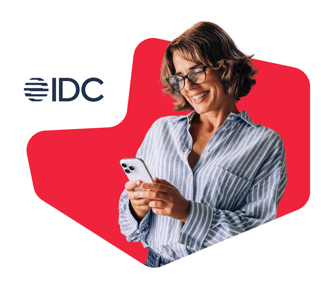 Woman in striped shirt smiling and looking at her smartphone with IDC logo in the background.