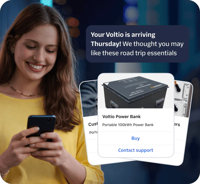 Woman smiling at phone with popup showing road trip essentials like a Voltiq power bank.