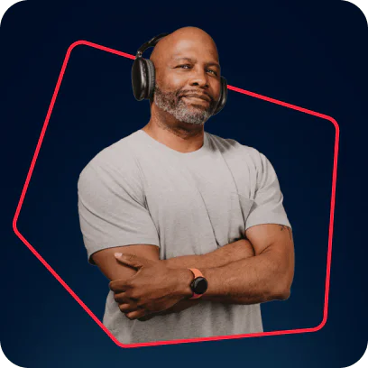 Man with headphones and smartwatch standing with arms crossed against a dark background.