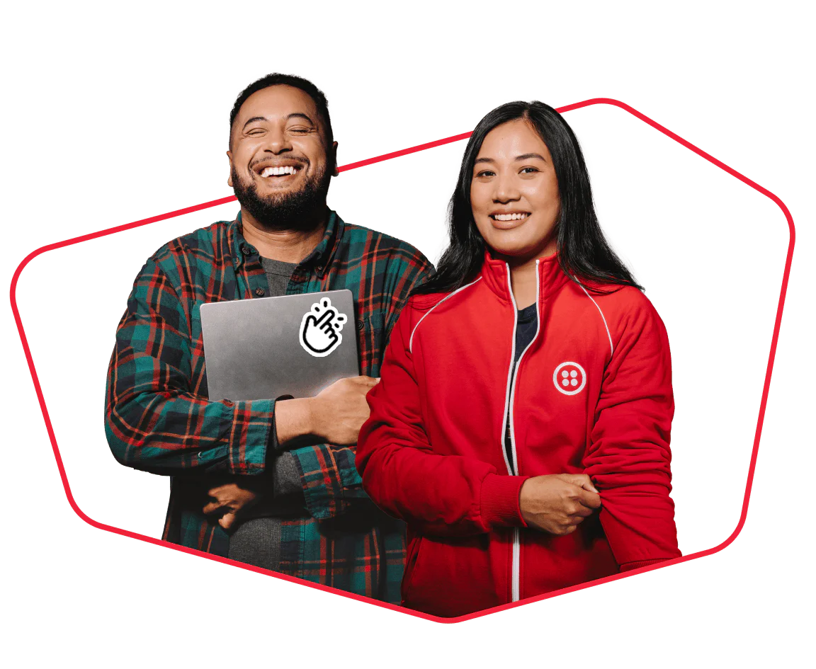 Two diverse people, one holding a laptop and the other in a red jacket, smiling confidently