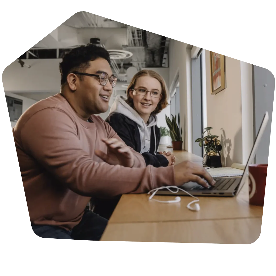 Two colleagues working together on a laptop in a bright office space.