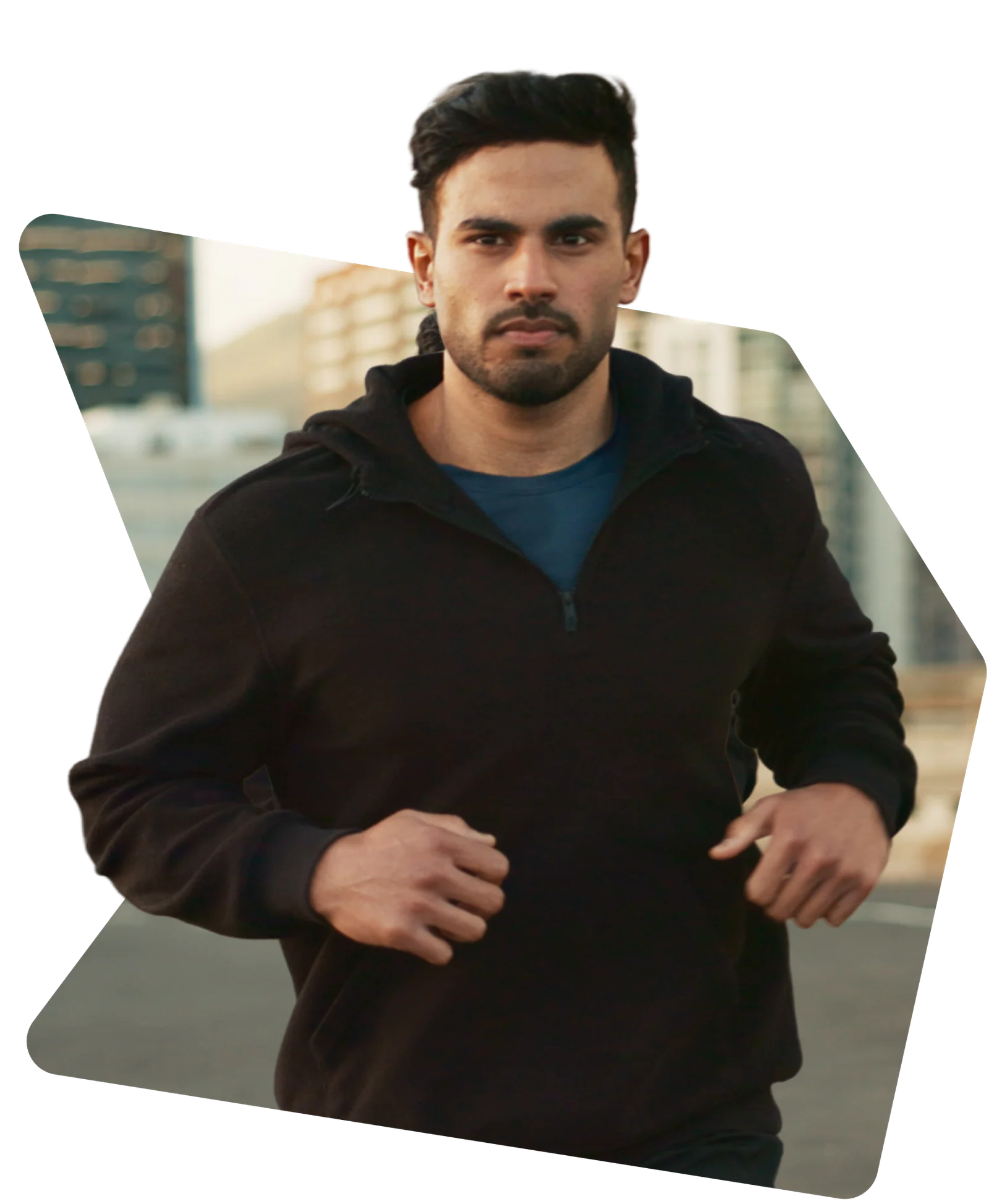 Man in black running jacket jogging on a city street in the evening.