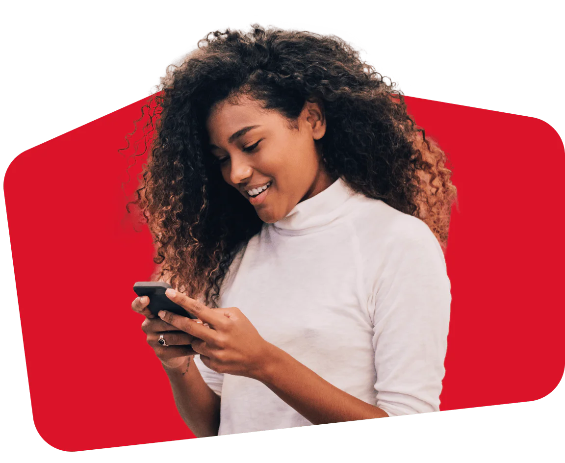 Woman Engaged with Smartphone on Red Background Woman looking at smartphone and smiling, against a red background.