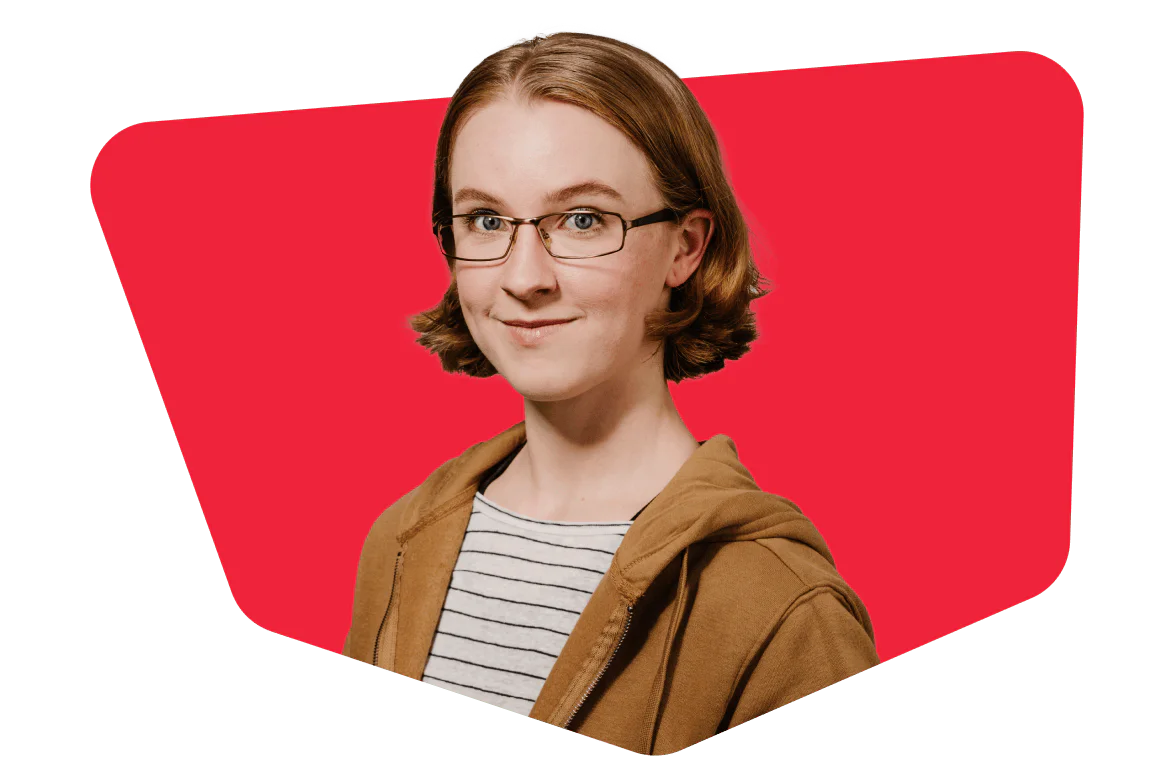 Person with glasses and short hair wearing a brown jacket and striped shirt on a red background