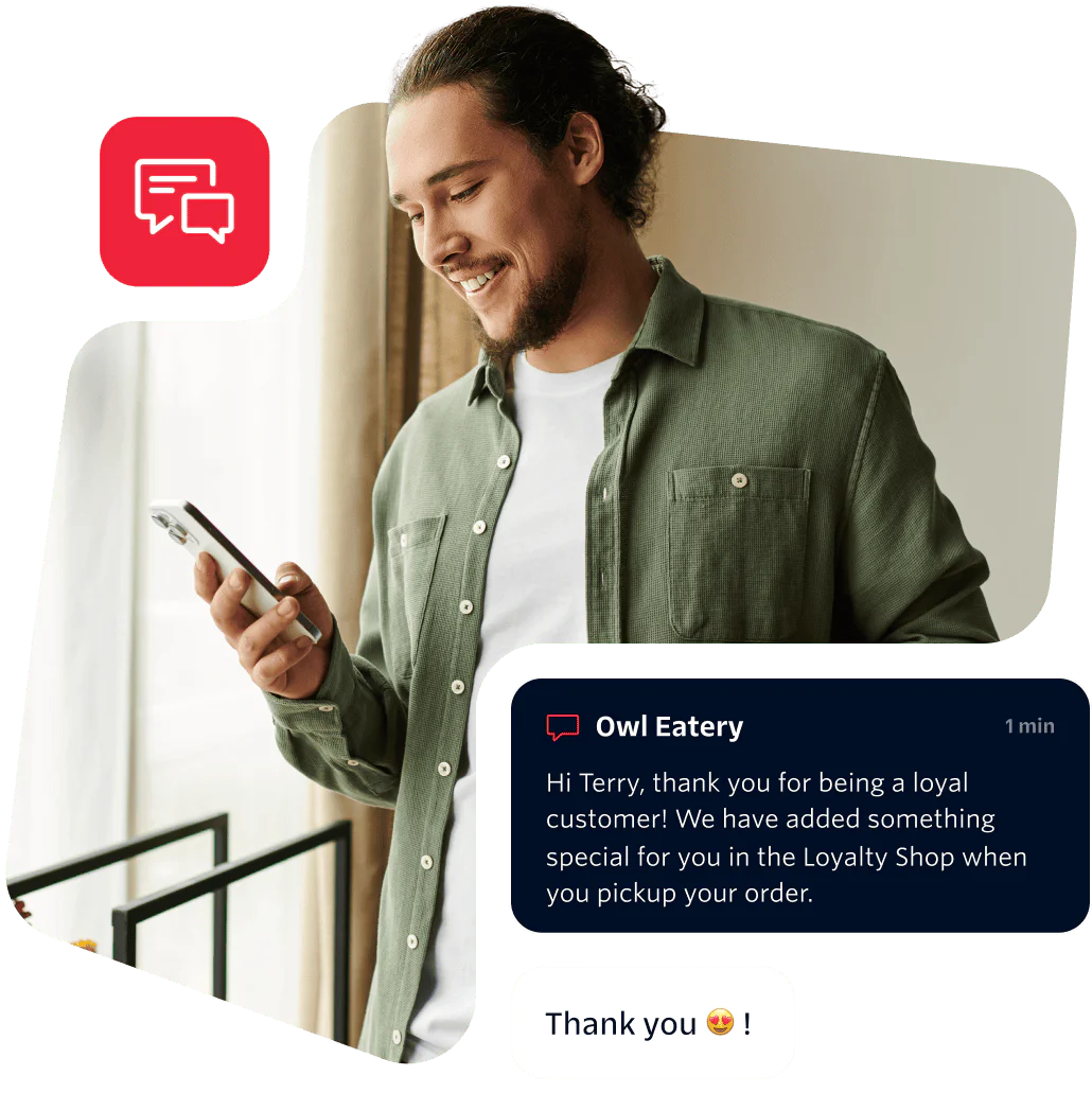 Man in green shirt reading a message on his phone with a smile on his face.