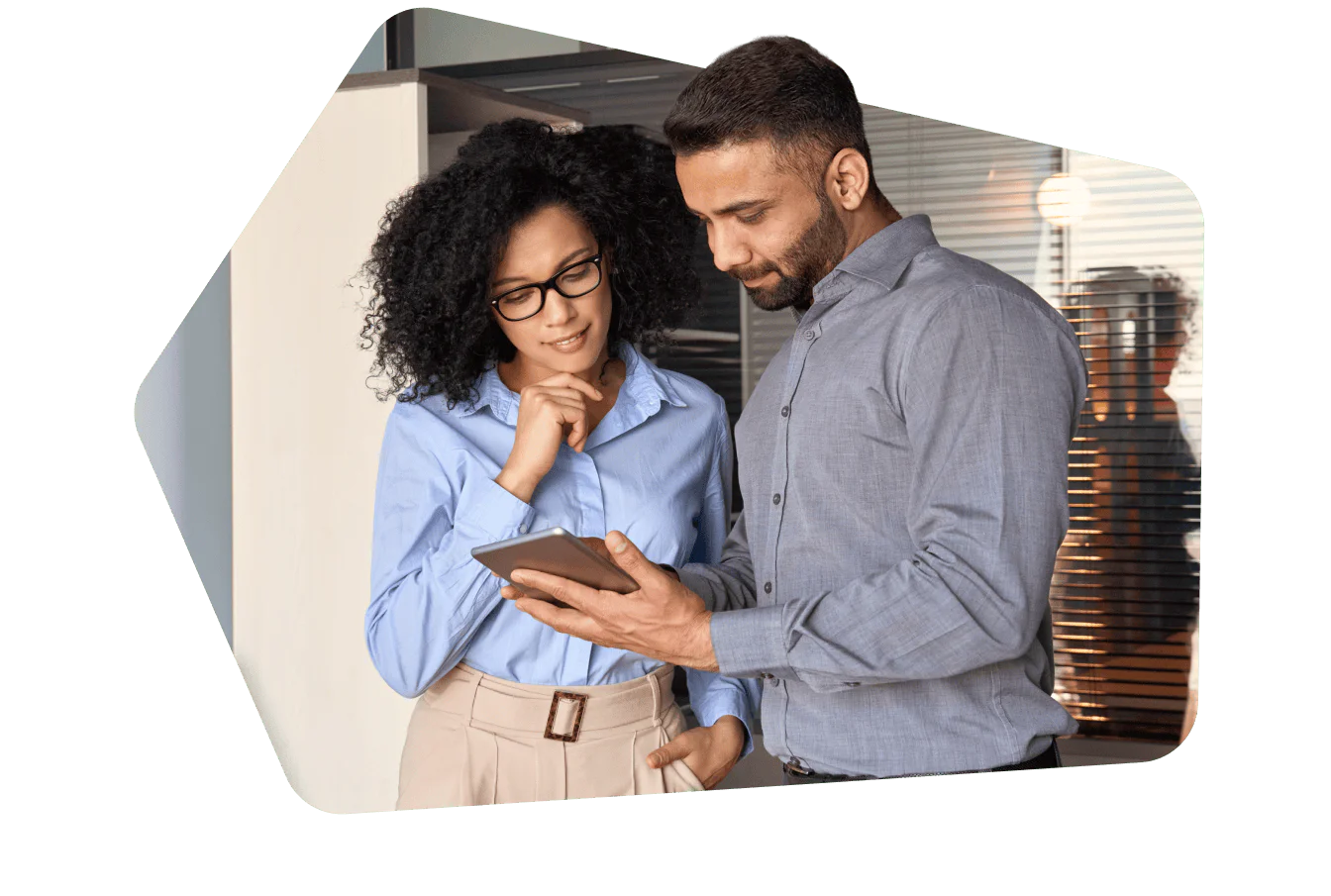 Two business professionals looking at a tablet in an office setting.
