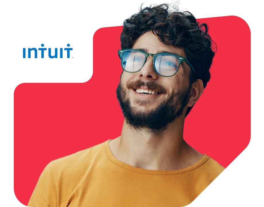 Smiling man talking on phone while using laptop, with Intuit logo in the corner.