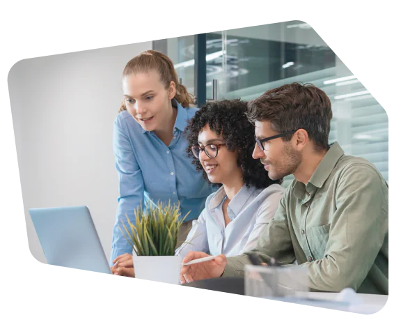 Three colleagues working together on a laptop in a modern office environment.