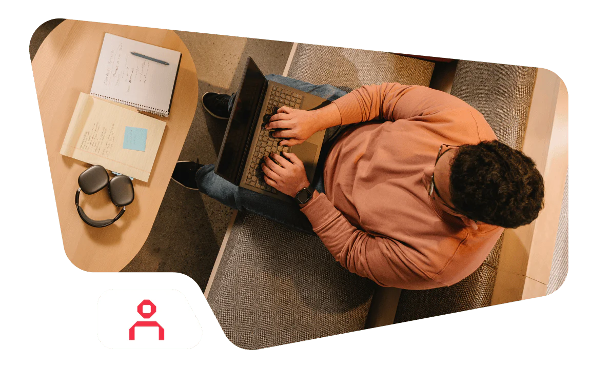 Person typing on a laptop with notes and headphones on a table.