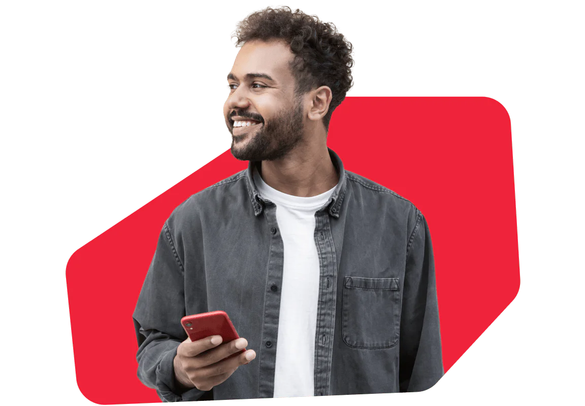 A smiling man in a gray shirt holds a smartphone against a red background
