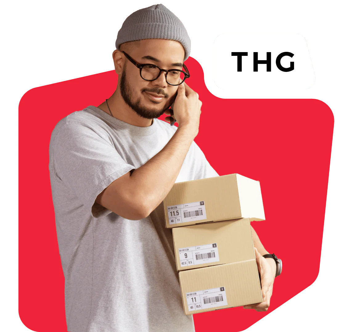 Man in gray beanie and glasses holding packages while on the phone