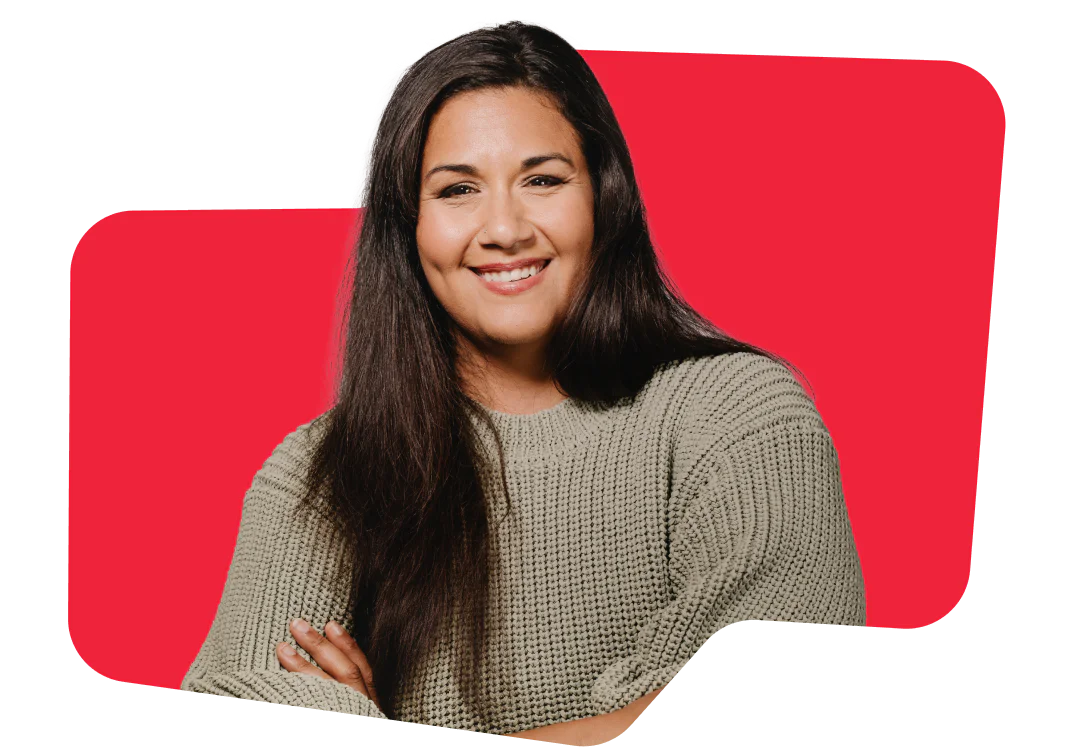 Confident woman smiling against a red background Smiling woman with long dark hair, wearing a beige sweater, in front of a red background