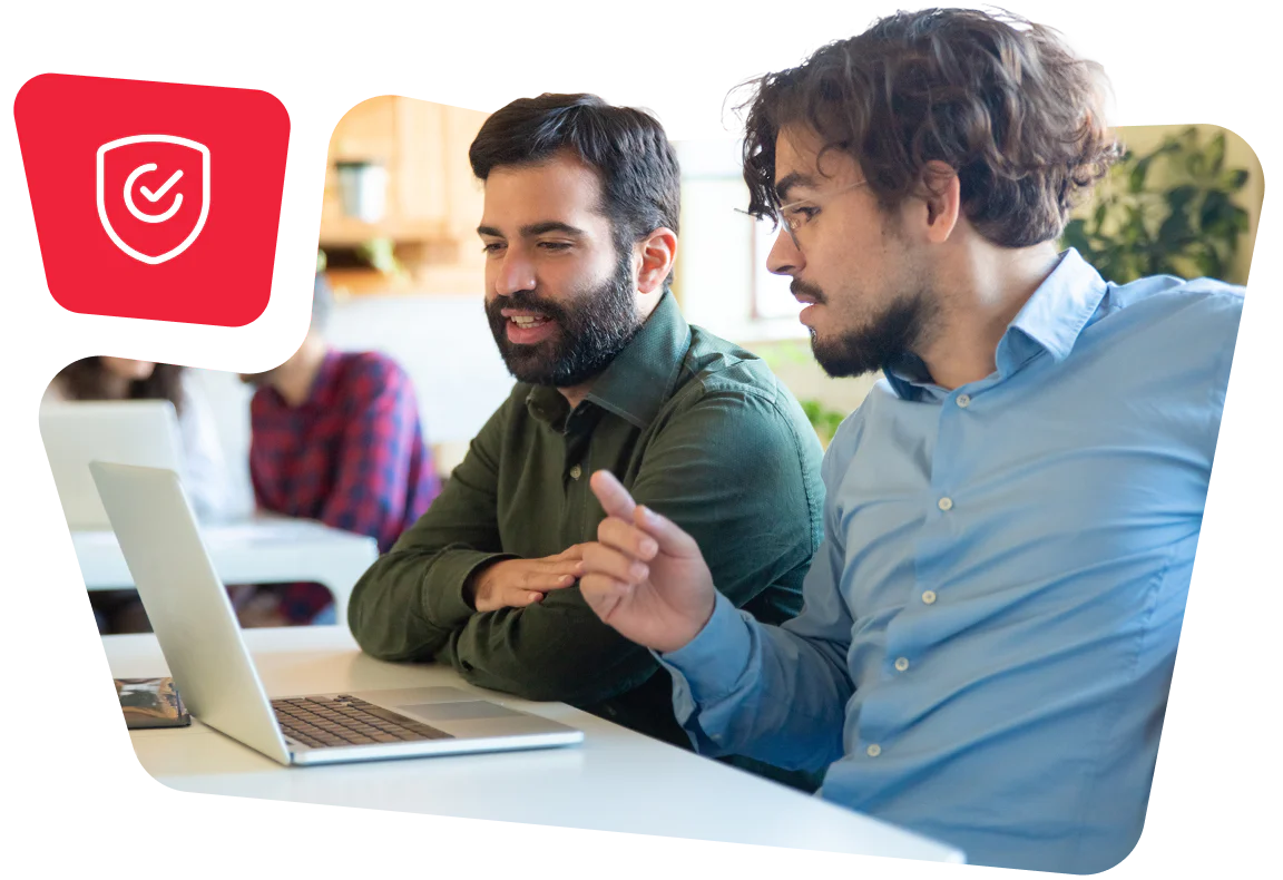 Two men looking at a laptop next to a security shield icon.