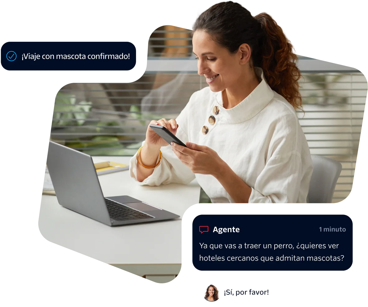 Woman using phone while chatting with virtual agent about pet-friendly hotels, laptop on desk.