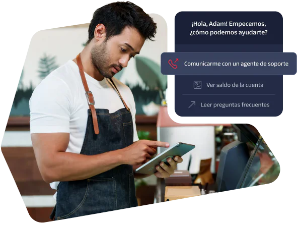 A barista in an apron using a tablet with a customer support prompt displayed on the screen.