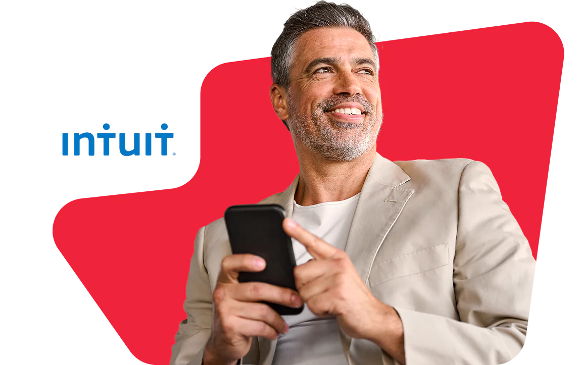 Smiling man holding a smartphone with Intuit logo in the background.