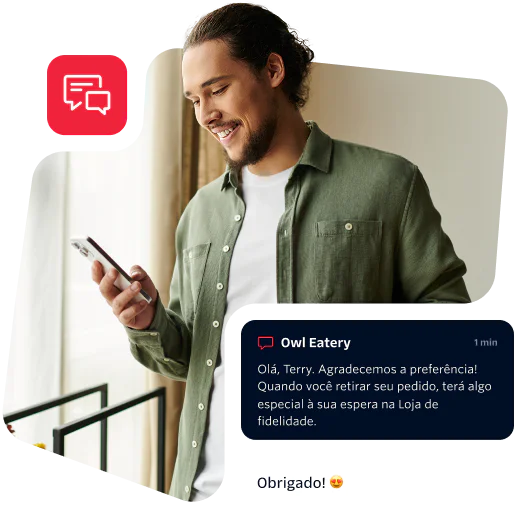 Man in green shirt reading a message on his phone with a smile on his face.