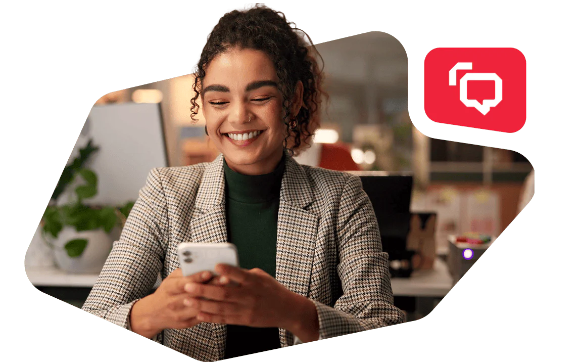 Businesswoman in a plaid blazer looking at her phone and smiling in an office setting.