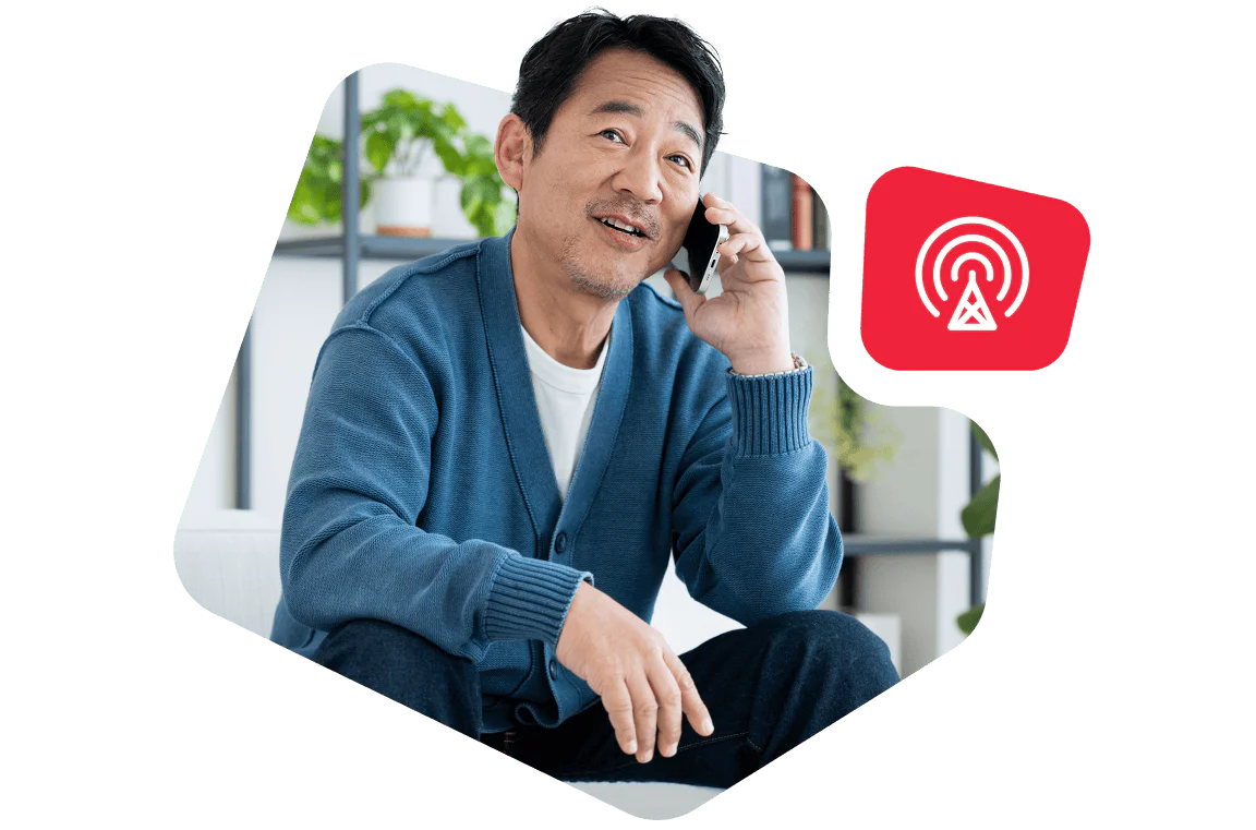 Man in a blue sweater sitting and talking on the phone, with a red network symbol beside him.
